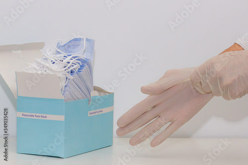 Obraz na płótnie Women's hands putting on rubber gloves and a pack of face masks, white background w salonie