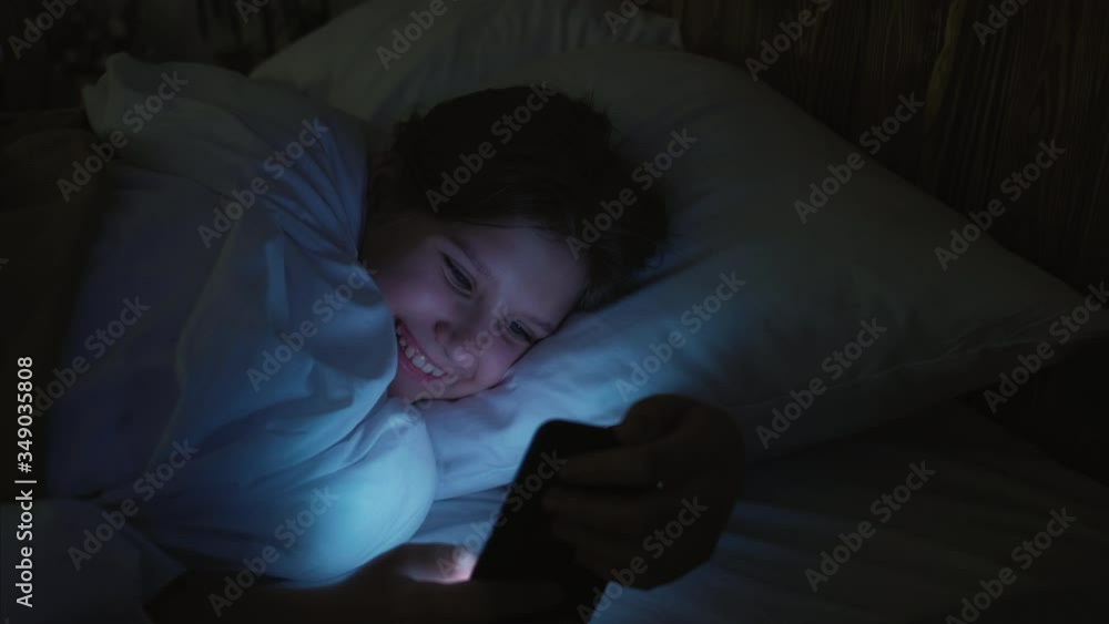 Teen leisure. Night Internet surfing. Girl scrolling app with memes on smartphone before sleep. Teen leisure. Night Internet surfing. Girl scrolling app with memes on smartphone before sleep.