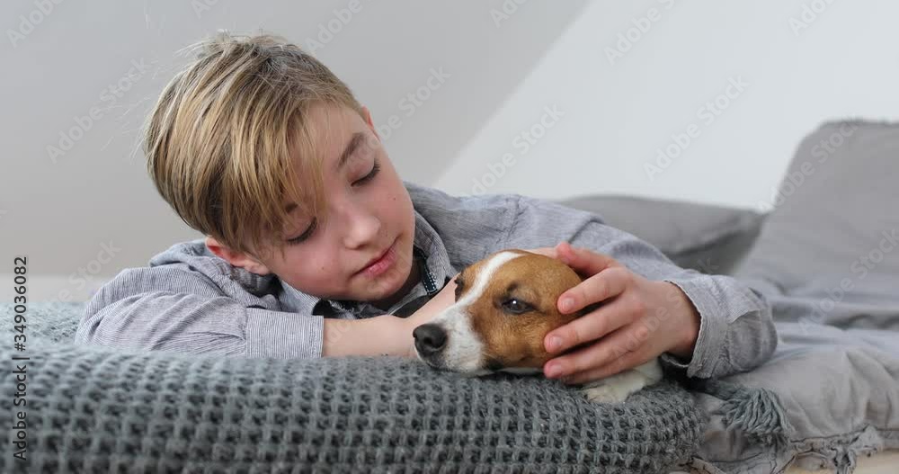 Boy cuddling his dog lying on bed Boy cuddling his dog lying on bed