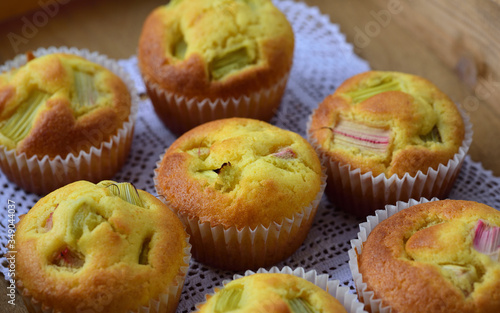 Freshly baked rhubarb muffins are on a wooden tray with a white tip