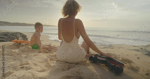 Boy with his mother sit on beach and looking at sea. photo