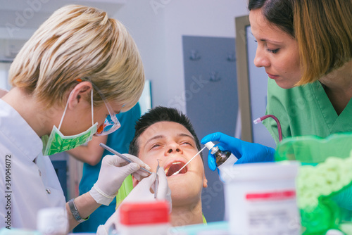Closeup picture of a female dentist examining teenage boy s teeth in the dental office.