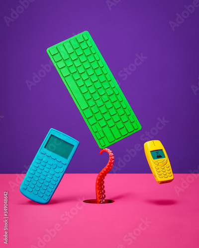 Calculator Keyboard and Cell Phone Floating and Balancing on Pink Surface with Purple Background (ID: 349048642)