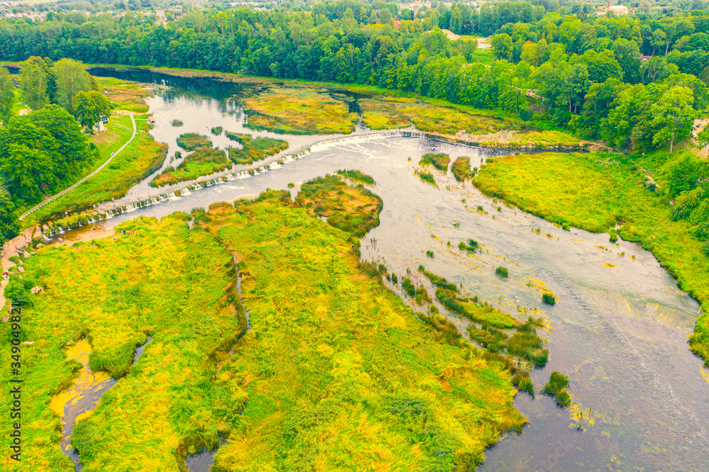 Beautiful panoramic aerial view photo from flying drone to Venta Rapid waterfall,the widest waterfall in Europe and the third longest brick bridge in Europe on a summer day in Kuldiga, Latvia.(series)