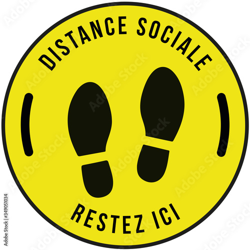 Panneau sur la mesure "distance sociale" et "restez ici" écrit en noir dans un rond jaune avec des trace de pas