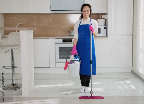 Young beautiful girl holding a mop in her hands on a white kitchen background. photo