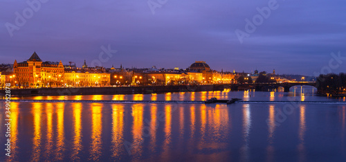 Panorama of historic buildings facades reflection in the Vltava river during the blue hour, Prague, Czech Republic.