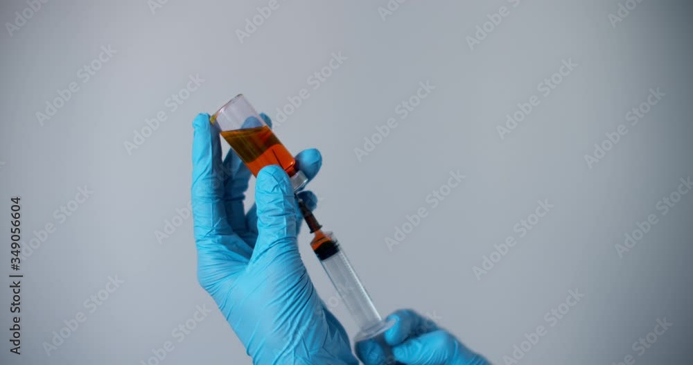 Medicine vaccination equipment with needle and ampoule in doctor or nurse hand isolated on white background. Health care concept. Hand holding syringe and vaccine. Ampoule with a vaccine orange or red Medicine vaccination equipment with needle and ampoule in doctor or nurse hand isolated on white background. Health care concept. Hand holding syringe and vaccine. Ampoule with a vaccine orange or red