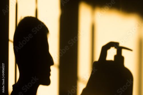 use disinfectant. silhouette of a man in a window with sanitizer against coronavirus. Social distancing.covid-19 