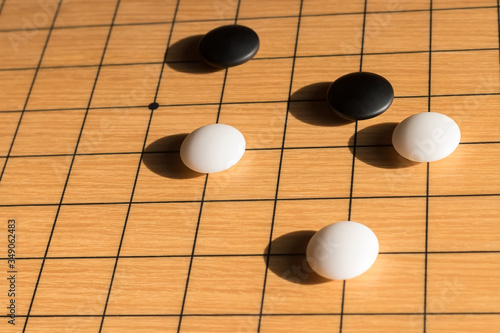 Wooden board for playing chinese game go (goban), side view, black and white stones in the bright rays of the sun