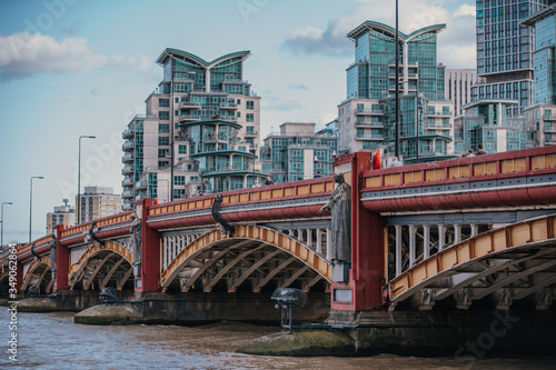 vauxhall bridge panorama with bright sky and clouds and beautiful and modern apartment buildings in the background, vauxhall bridge over the thames river in daytime photo