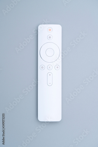 A white remote control placed on a blue-gray background.