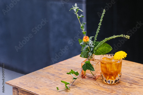 Yellow cocktail with flowers on the dark background