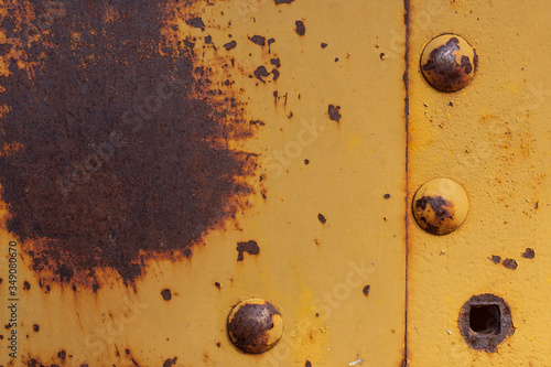 Fondo y textura de chapa de metal pintada de amarillo oxidada con remaches.