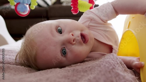 Naughty baby lies on her side under her jungle gym trying to escape photo