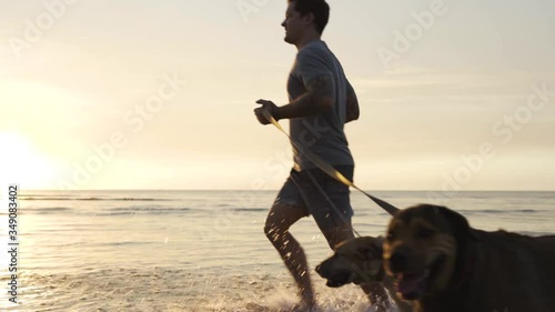 Man running with his dogs in a beach of Australia in slow motion.