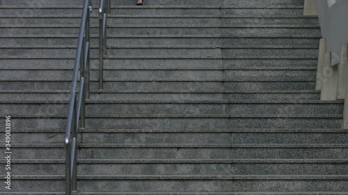 Beautiful young female walking down the stairs. Full body of businesswoman confidently walking in heels wearing business smart clothes. Red hair girl looks at the camera  and smiles. photo