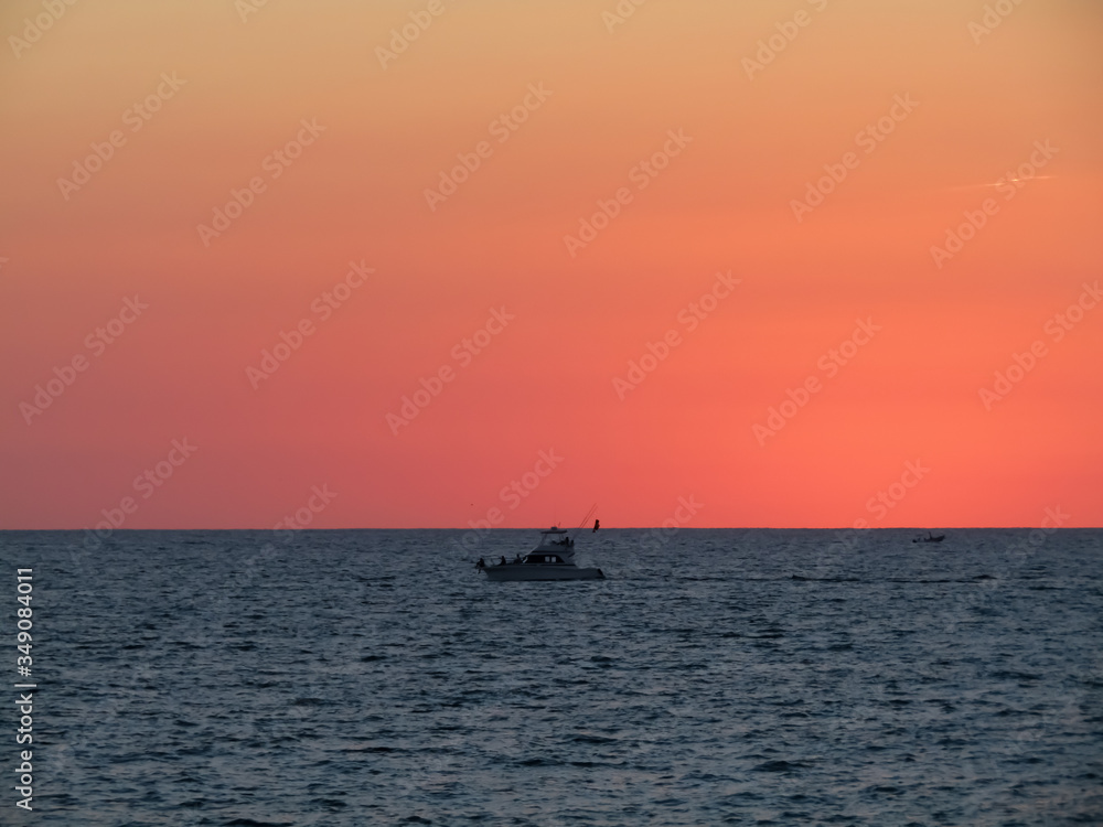 Motorboat crosses the sea in a stunning sunset with red sky in Mazatlan Mexico