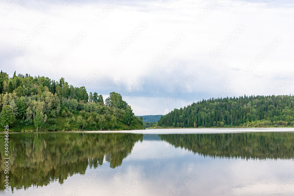 large lake surrounded by taiga in cloudy weather