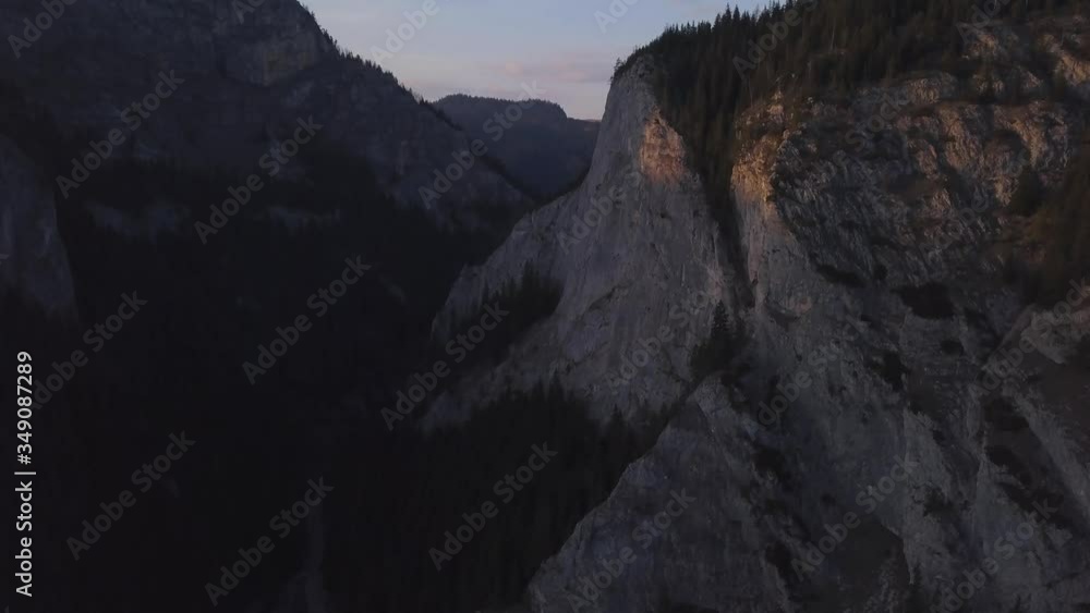Fading daylight leaves hint of red and purple on cliff face of deep gorge in Romania. Aerial sunset view of mountains and immense valley popular with rock climbers. Wild Ferenc of Via Ferrata. Fading daylight leaves hint of red and purple on cliff face of deep gorge in Romania. Aerial sunset view of mountains and immense valley popular with rock climbers. Wild Ferenc of Via Ferrata.