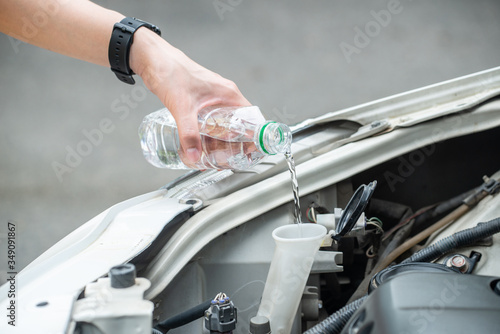 Cropped shot of person hand filling water into car radiator for reduce engine overheating. Engines can overheat because something’s wrong within the cooling system and heat isn’t able to escape.