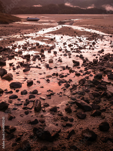 Crimson sunset in tropical inlet/bay with deserted boat in frame. Portrait shot made in Abel Tasman National Park, New Zealand photo