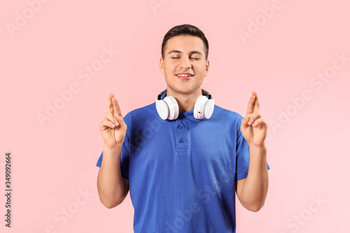 Portrait of young man with crossed fingers on color background © Pixel-Shot