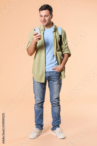 Foto Portrait of male student with mobile phone on color background