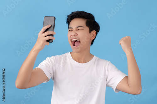 Portraits of Asian people, happy and looking at a smartphone. Isolated on a light blue background in the studio.