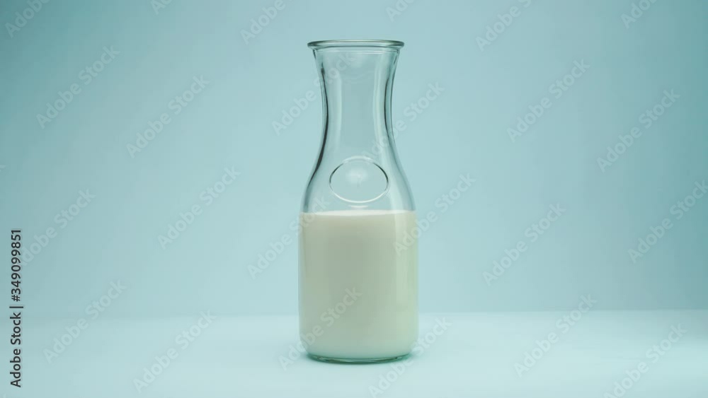 stop motion filling milk in glass bottle on light blue background stop motion filling milk in glass bottle on light blue background