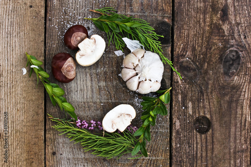 half of the mushrooms is cut for lunch in the fresh air, lies on a gray board with chestnuts and herbs. Circle frame.
