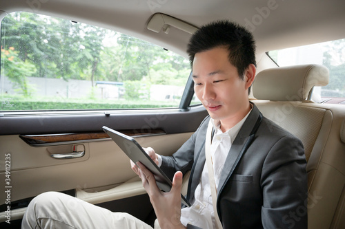 Handsome asian businessman working with tablet. Young executive manager Full concentration at work while sitting in the car. © komgritch