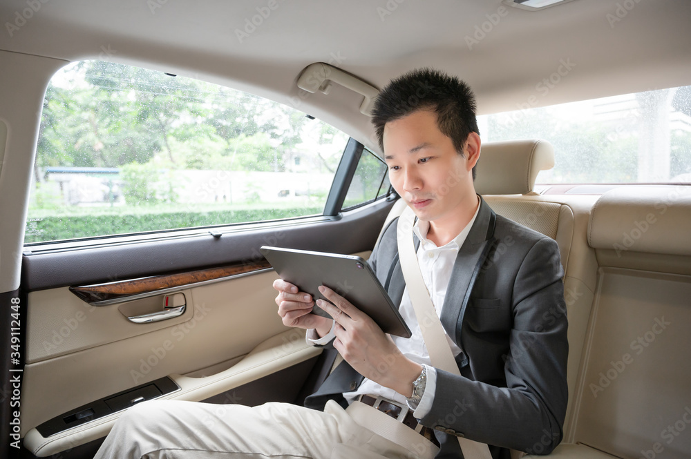 Handsome asian businessman working with tablet. Young executive manager Full concentration at work while sitting in the car.