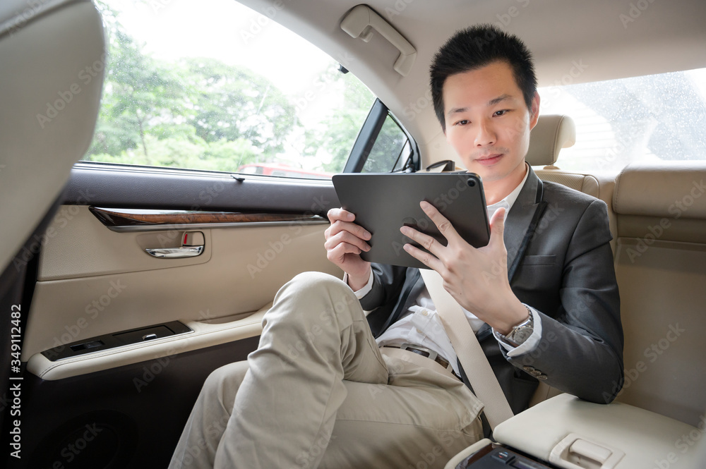 Handsome asian businessman working with tablet. Young executive manager Full concentration at work while sitting in the car.
