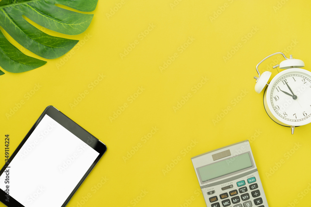 Top view modern digital tablet and calculator with alarm clock on yellow color background. Top view modern digital tablet and calculator with alarm clock on yellow color background.