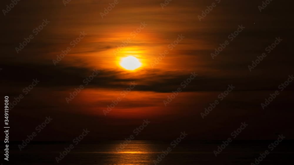 Time lapse of moon rising up above the sea
