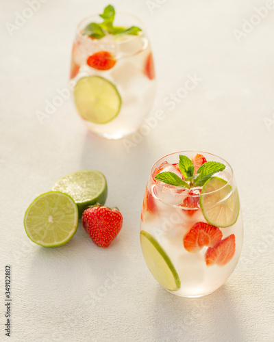 Fresh cold summer cocktail with lime, strawberry, mint and ice. Two glass with lemonade cocktail. Selective focus.