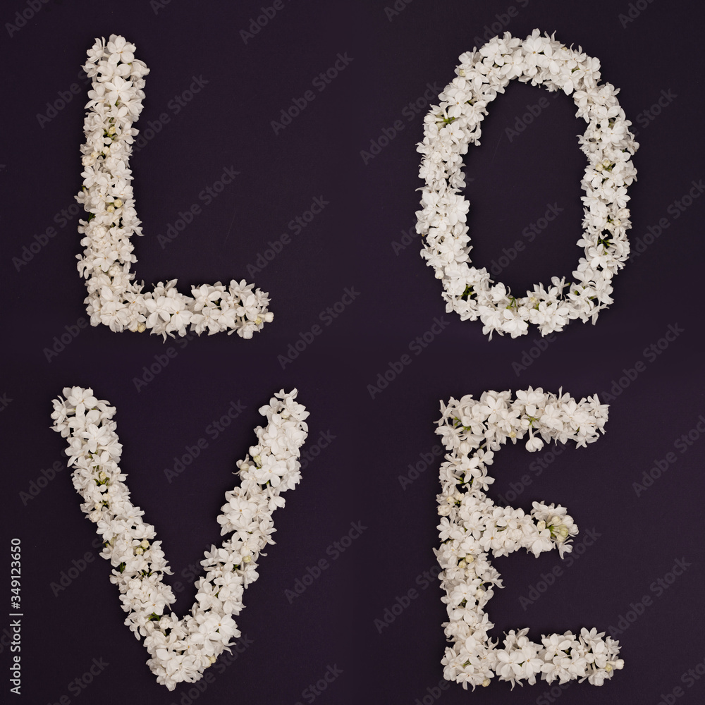 Spring flowers. White lilac flowers on a dark purple background. The Inscription Love. Top view, flat styling, copy space Spring flowers. White lilac flowers on a dark purple background. The Inscription Love. Top view, flat styling, copy space