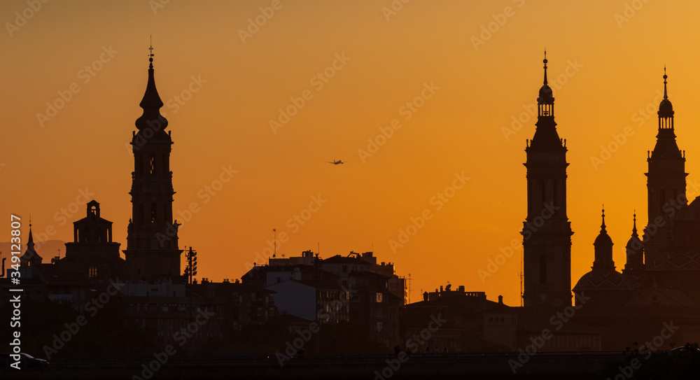 sunset in Zaragoza with seo cathedral and pilar cathedral in the background and a plane taking off
