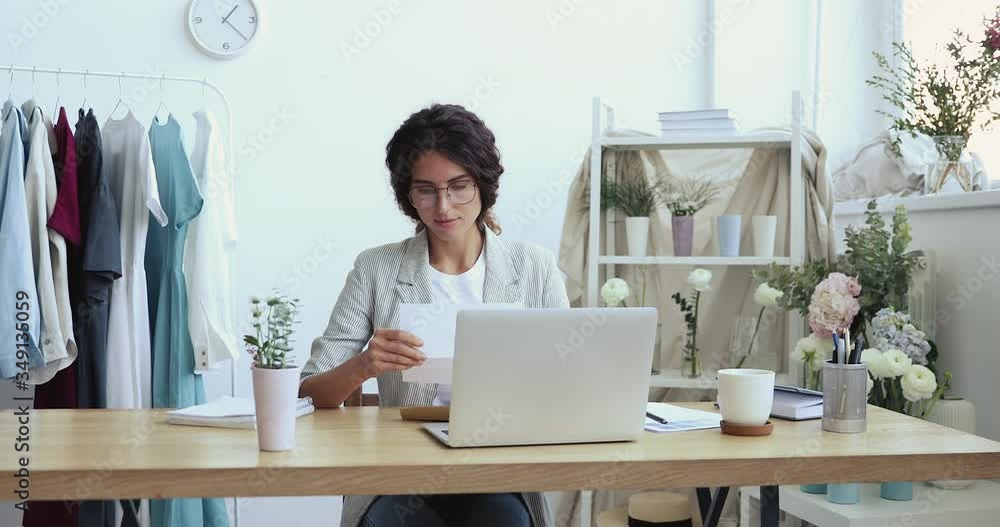 Excited overjoyed female entrepreneur fashion designer opening mail letter reading good news celebrating business success, receiving bank loan approval concept sitting at desk in modern studio. Excited overjoyed female entrepreneur fashion designer opening mail letter reading good news celebrating business success, receiving bank loan approval concept sitting at desk in modern studio.
