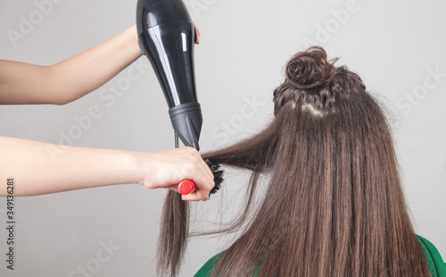 Girl drying hair with hairdryer in home.