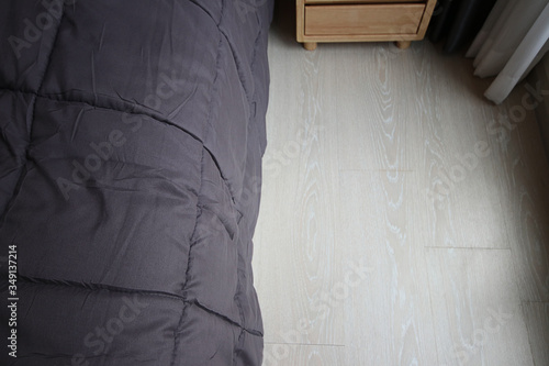 Close up grey bed sheet in bedroom, cozy interior decor with earth tone, Bed top view with wooden floor
