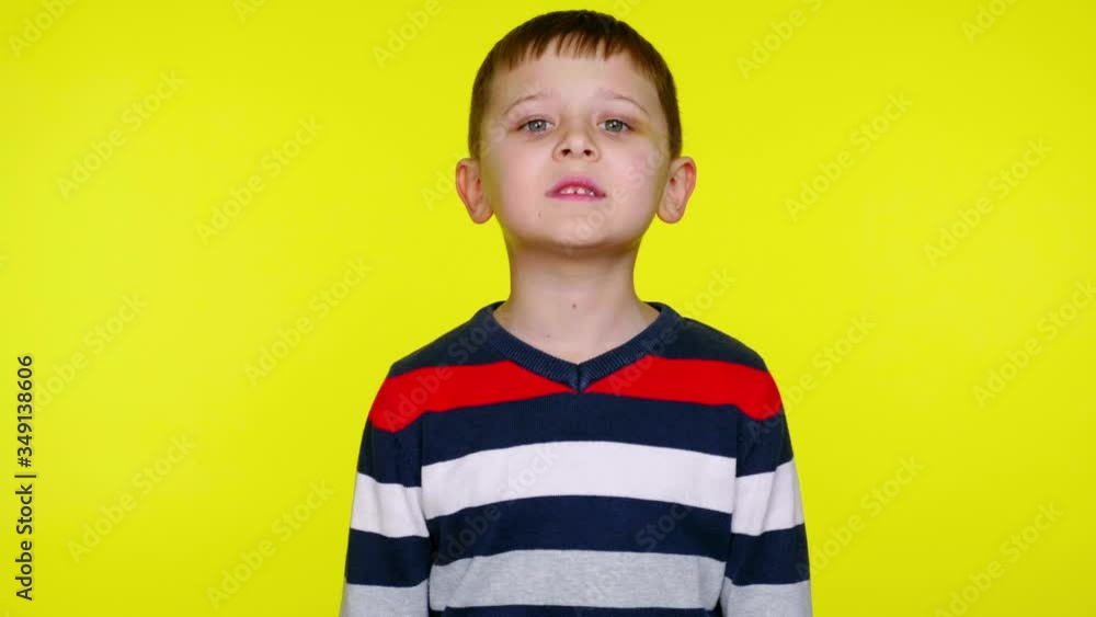Serious little child boy in a colorful sweater says yes on a yellow background with copy space. Place for text or product. 4K slowmotion footage Serious little child boy in a colorful sweater says yes on a yellow background with copy space. Place for text or product. 4K slowmotion footage