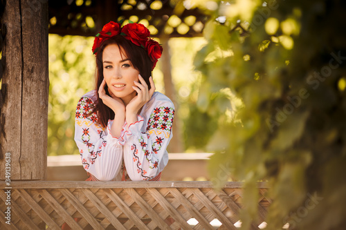 Young redhead moldavian girl dressed in traditional costume  with flower wreath on the head smiling,closeup portrait