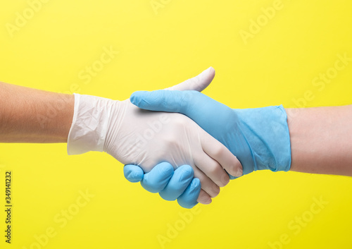 yellow background and hands in medical gloves. woman and a man. medical collaboration and doctors hold hands to each other