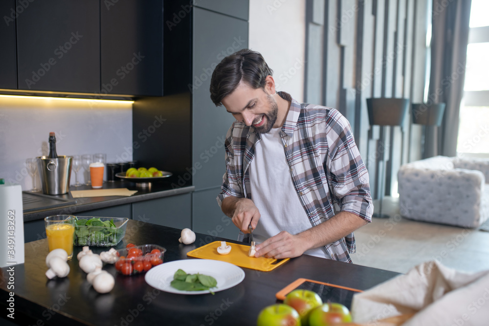 Smiling man slicing mushrooms on a cutting board. Smiling man slicing mushrooms on a cutting board.