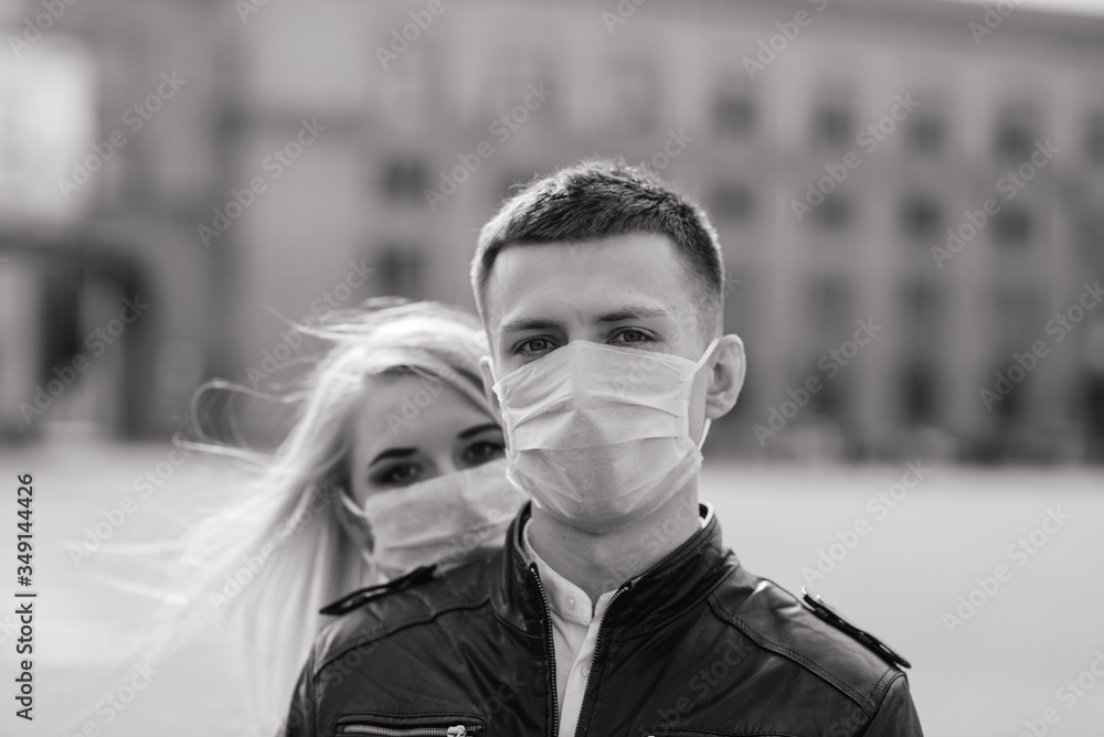 Obraz premium Young couple in love in protective medical mask on face outdoor at street. Environmental pollution concept. Guy and girl in virus protection