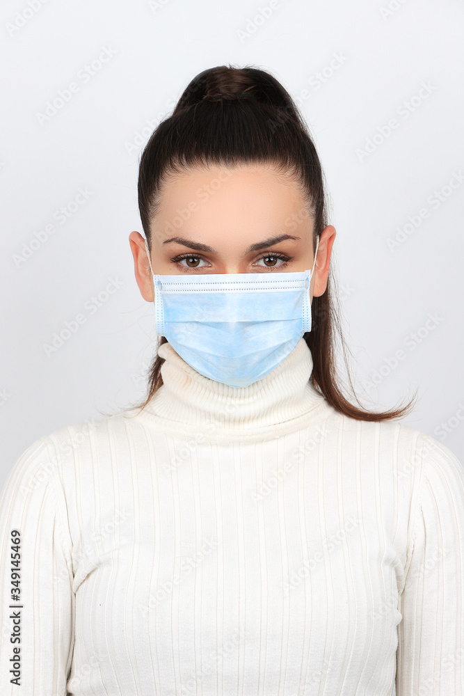 Jeune femme brune portant un masque chirurgical pour se protéger des virus isolée sur fond blanc Jeune femme brune portant un masque chirurgical pour se protéger des virus isolée sur fond blanc