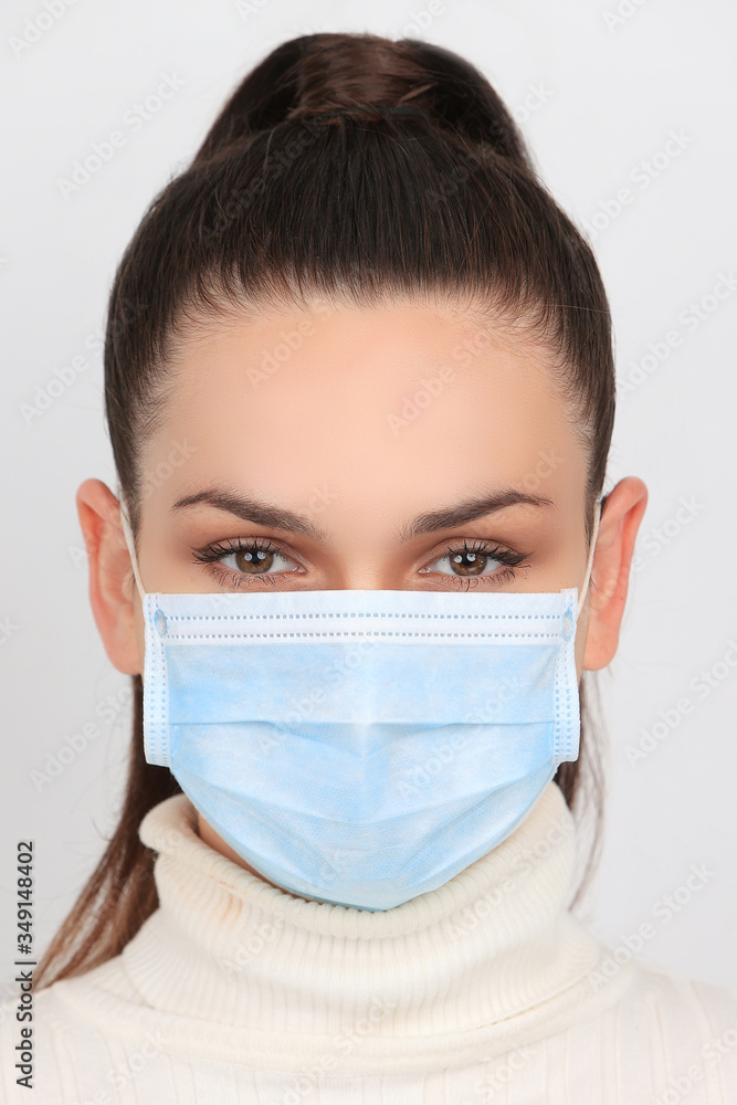 Jeune femme brune portant un masque chirurgical pour se protéger des virus isolée sur fond blanc Jeune femme brune portant un masque chirurgical pour se protéger des virus isolée sur fond blanc