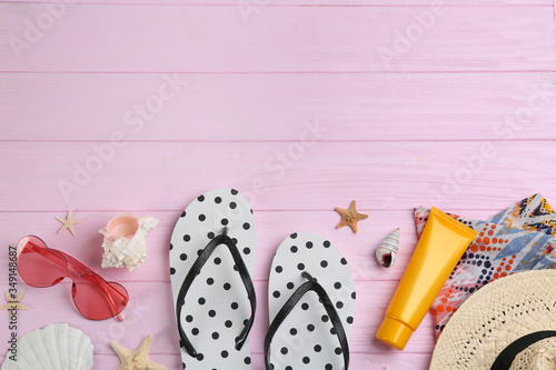 Flat lay composition with flip flops and beach accessories on pink wooden background. Space for text